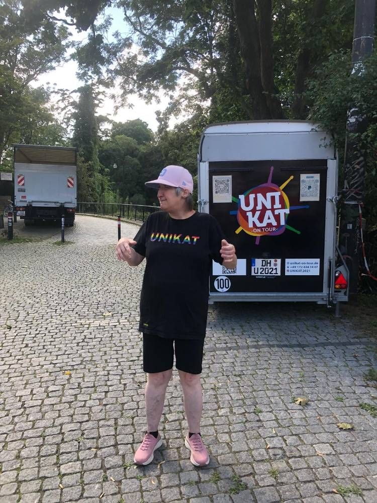 Teilnehmerin vor dem Anhänger mit dem UNIKAT-Logo