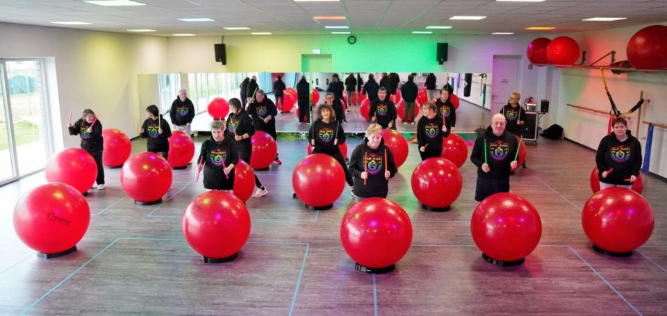 Blick in die Halle: viele Trommelnde stehen an roten Gymnastikbällen