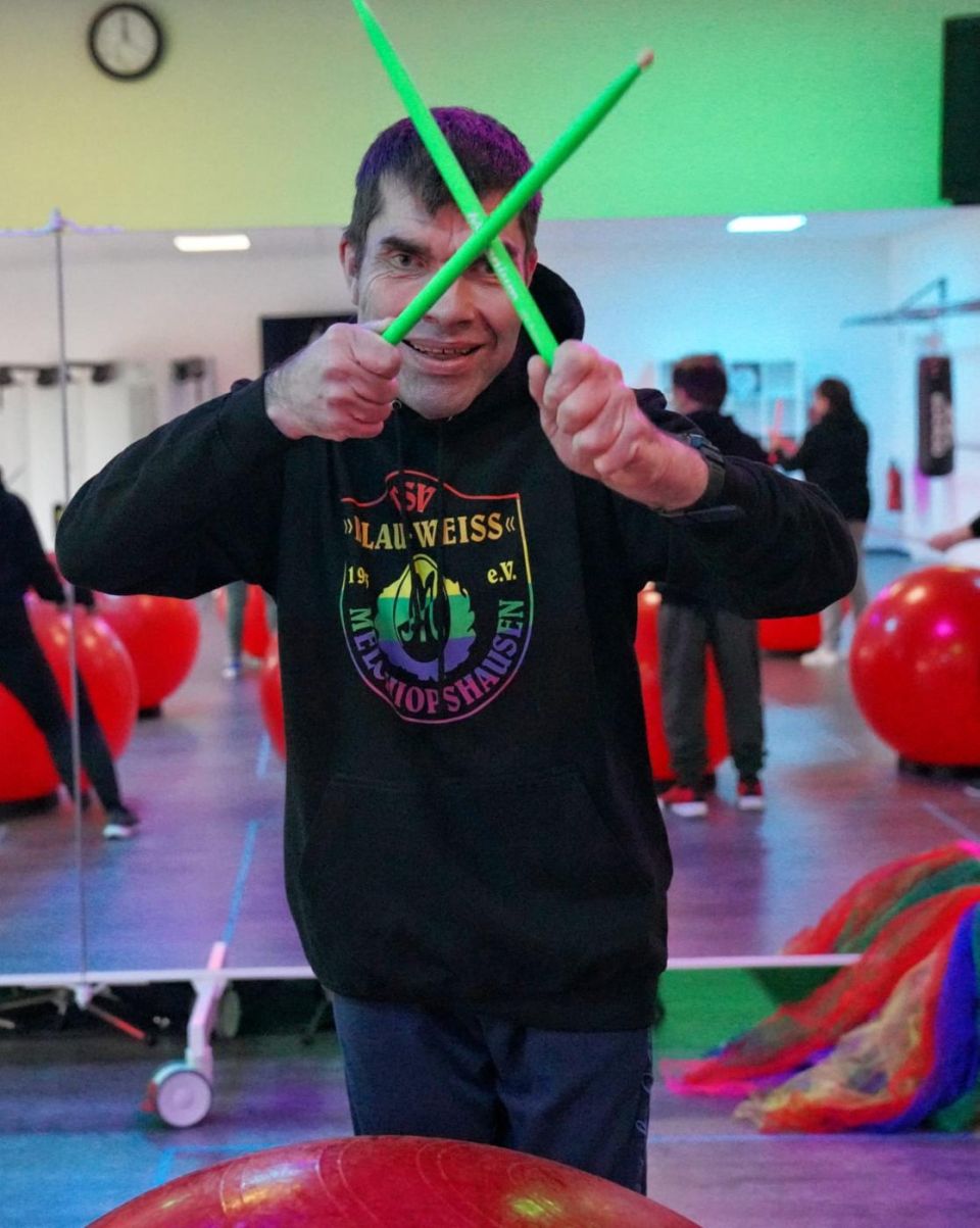Trommler kreuzt die grünen Sticks vor dem Gesicht